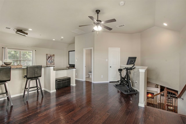 interior space featuring a lit fireplace, visible vents, lofted ceiling, and wood finished floors