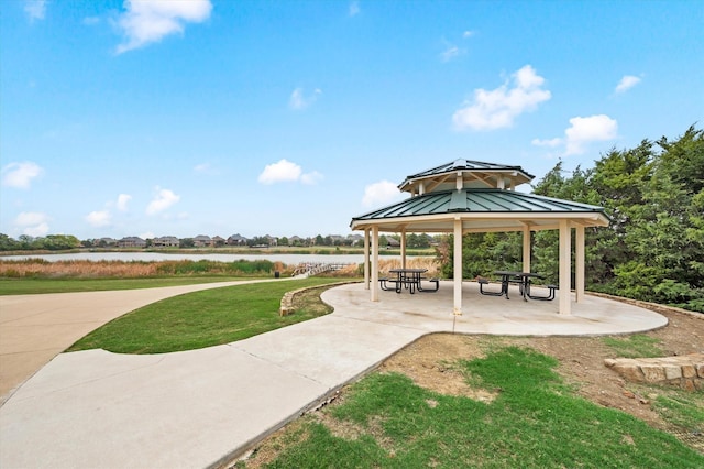 view of property's community with a gazebo, a lawn, a patio, and a water view