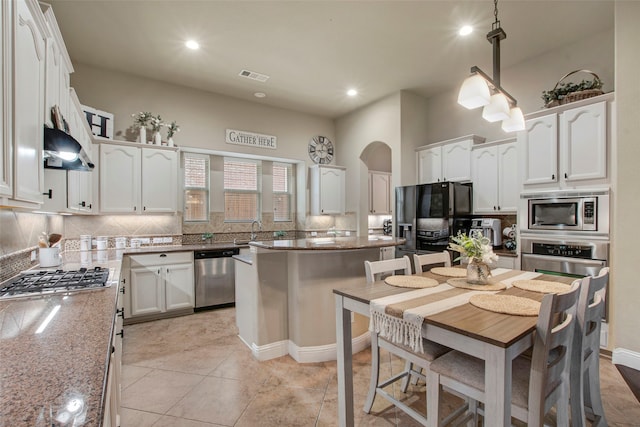 kitchen with arched walkways, white cabinetry, and stainless steel appliances