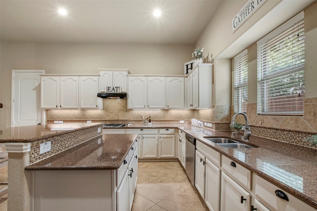 kitchen with dark stone counters, stainless steel appliances, a sink, white cabinets, and backsplash