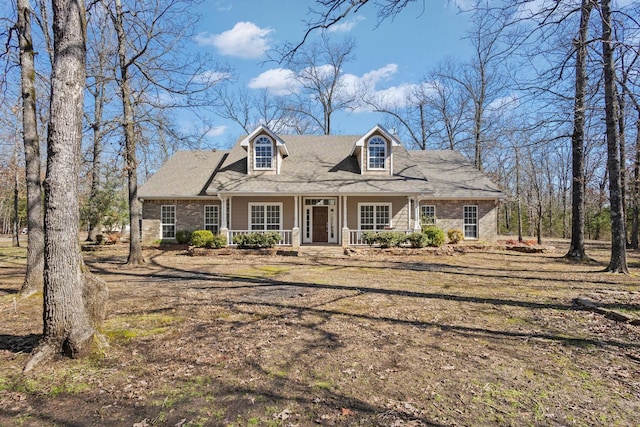 new england style home featuring brick siding and a porch