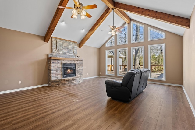 living room with wood finished floors, beamed ceiling, a ceiling fan, and a brick fireplace