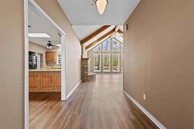 hallway with dark wood finished floors, lofted ceiling with beams, and baseboards