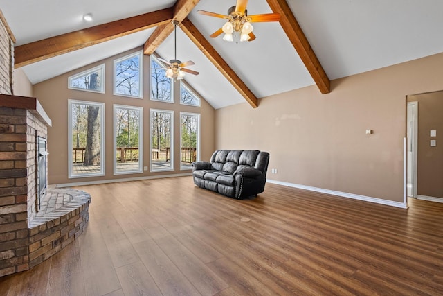 living area featuring wood finished floors, ceiling fan, beamed ceiling, and a brick fireplace