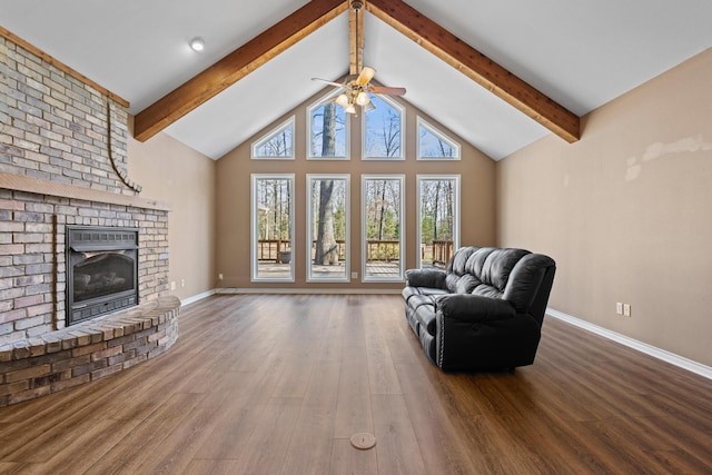 living area featuring beamed ceiling, baseboards, wood finished floors, and a fireplace