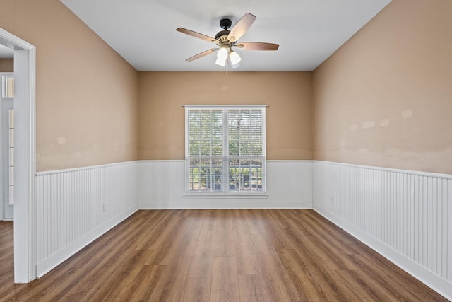 unfurnished room with a wainscoted wall, ceiling fan, and wood finished floors