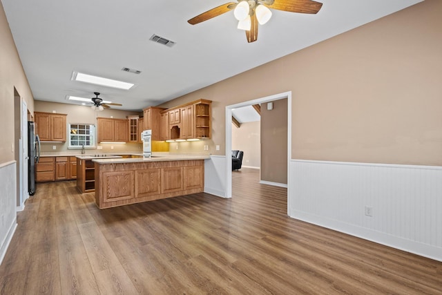 kitchen featuring open shelves, a skylight, light countertops, and freestanding refrigerator