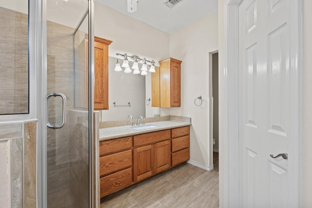 bathroom featuring visible vents, toilet, wood finished floors, a shower stall, and vanity