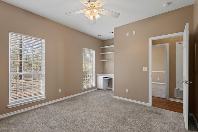 unfurnished bedroom featuring visible vents, light colored carpet, a ceiling fan, and baseboards