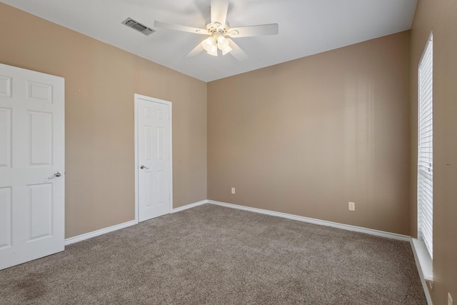 unfurnished bedroom featuring multiple windows, carpet flooring, baseboards, and visible vents