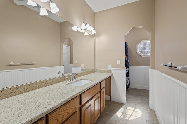 full bath with vanity and a wainscoted wall