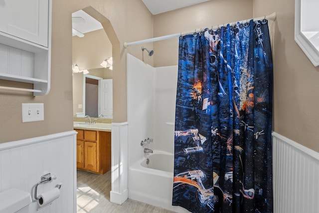 bathroom featuring vanity, shower / bath combo, and wainscoting