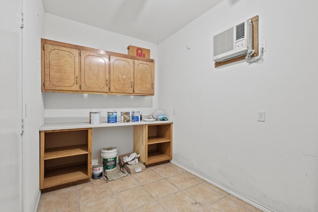 clothes washing area featuring an AC wall unit and light tile patterned flooring