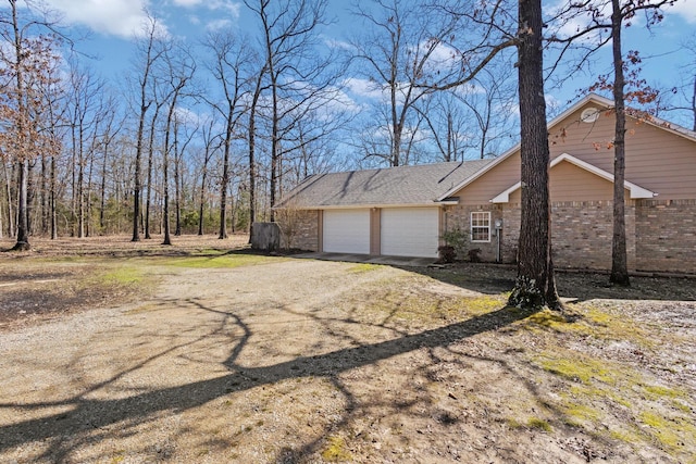 view of property exterior with brick siding, driveway, and an attached garage