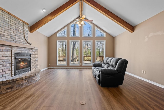 unfurnished living room with beamed ceiling, ceiling fan, wood finished floors, and a fireplace