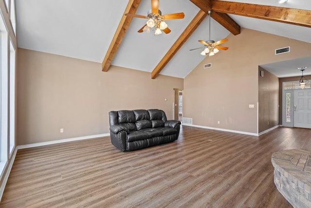 living area with visible vents, baseboards, beam ceiling, wood finished floors, and high vaulted ceiling