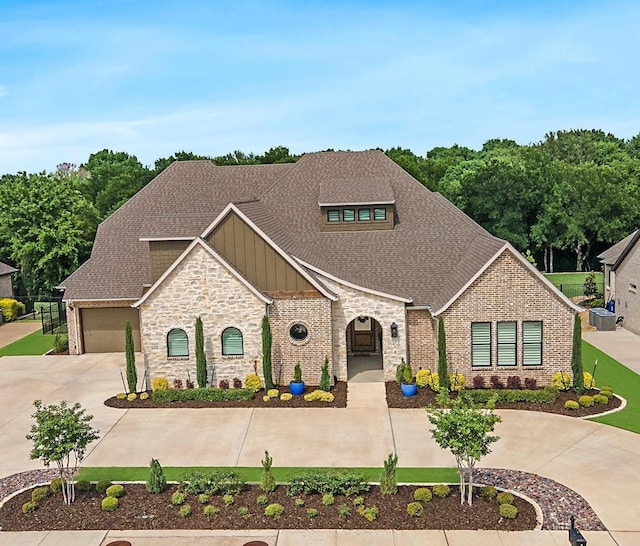 view of front of property featuring concrete driveway, brick siding, board and batten siding, and roof with shingles