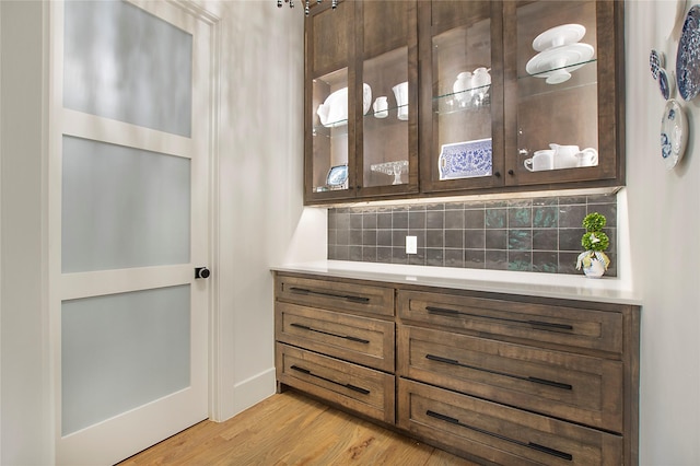 bar featuring decorative backsplash and light wood-style floors