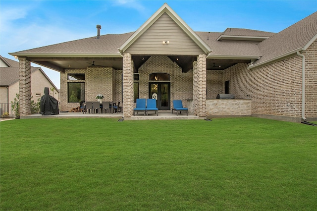 back of house with a patio area, brick siding, and a yard