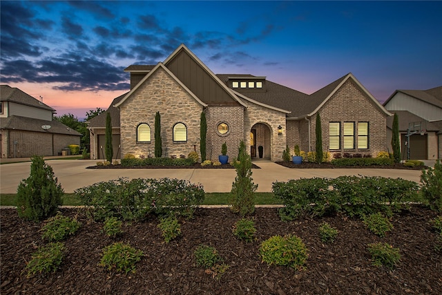 view of front of house featuring board and batten siding, stone siding, brick siding, and driveway