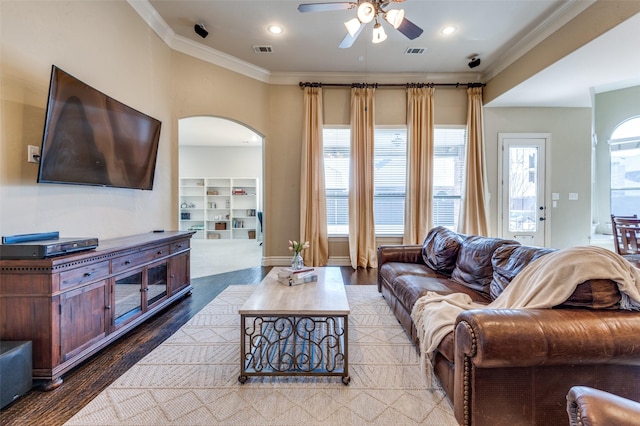 living area featuring wood finished floors, visible vents, and ornamental molding