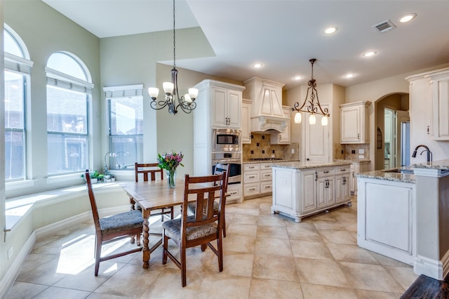 kitchen featuring visible vents, backsplash, arched walkways, appliances with stainless steel finishes, and a chandelier