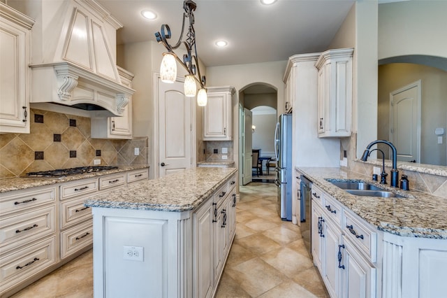 kitchen featuring a sink, arched walkways, appliances with stainless steel finishes, decorative backsplash, and custom exhaust hood