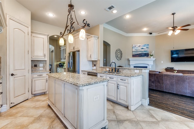 kitchen featuring visible vents, open floor plan, a peninsula, arched walkways, and stainless steel appliances