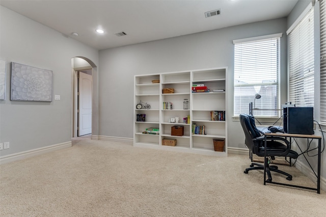 office space with arched walkways, visible vents, plenty of natural light, and carpet floors