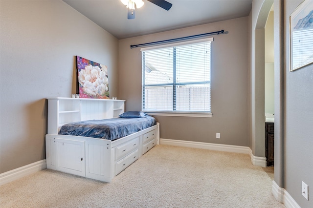 bedroom with baseboards, light colored carpet, ceiling fan, and arched walkways