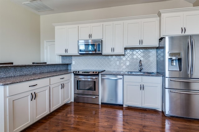 kitchen featuring a sink, dark wood-type flooring, dark stone countertops, and stainless steel appliances