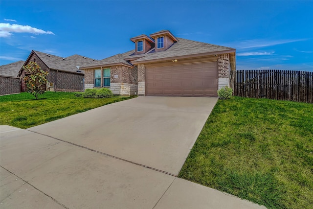 view of front facade with brick siding, fence, concrete driveway, a front yard, and an attached garage