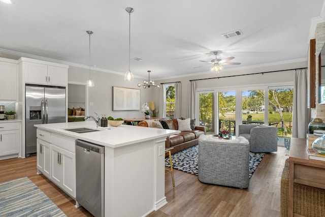 kitchen featuring crown molding, open floor plan, light wood-style floors, stainless steel appliances, and a sink