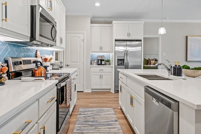 kitchen featuring white cabinetry, stainless steel appliances, crown molding, and a sink