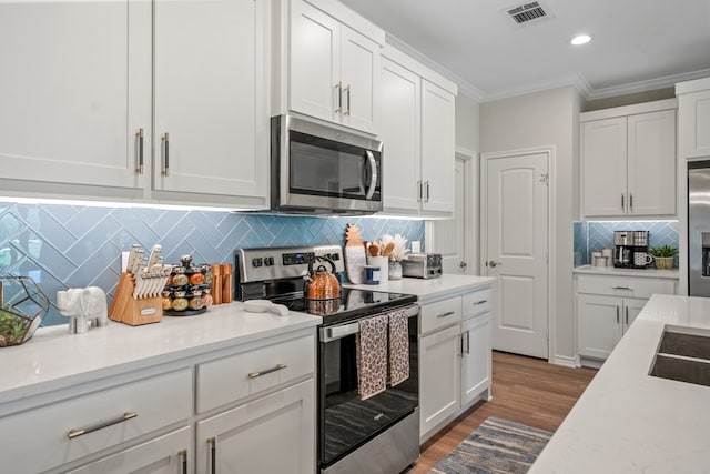 kitchen featuring crown molding, white cabinets, visible vents, and stainless steel appliances