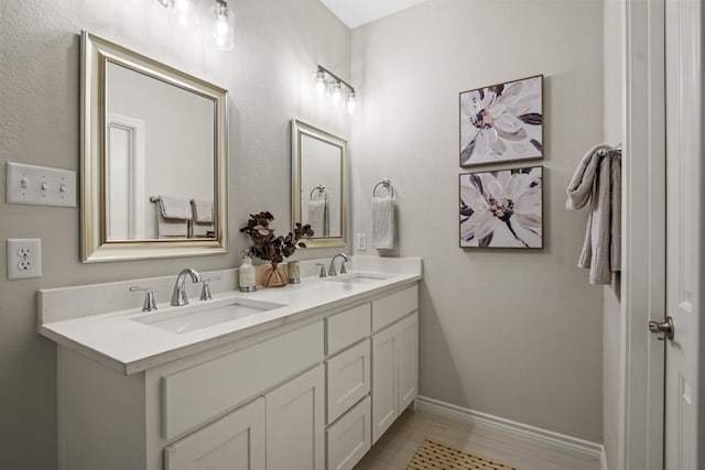 full bathroom featuring a sink, baseboards, and double vanity