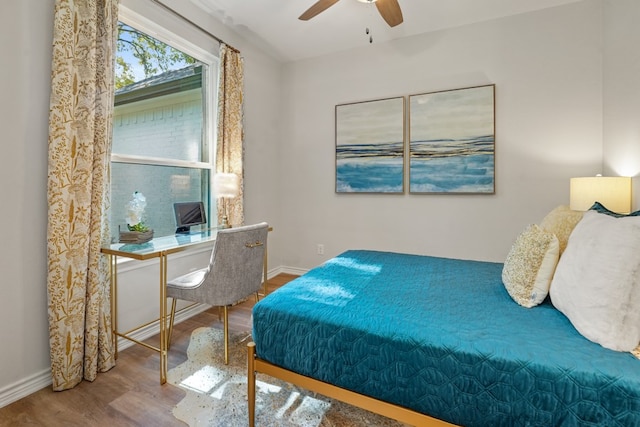 bedroom with a ceiling fan, wood finished floors, and baseboards