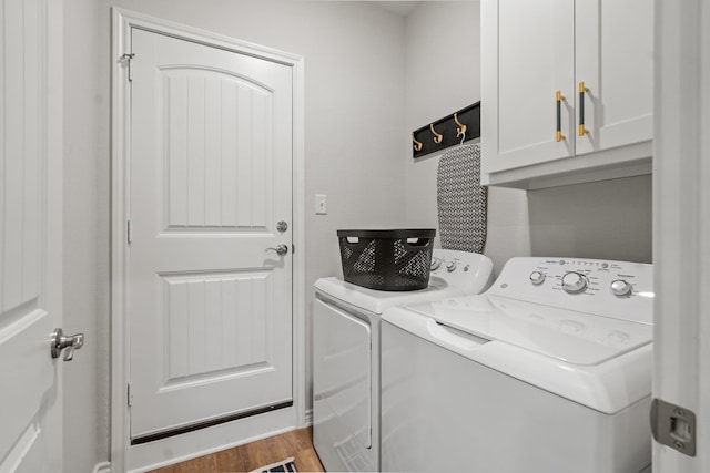 laundry area with washer and clothes dryer, cabinet space, and wood finished floors