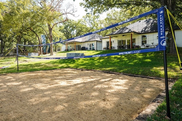 back of property featuring a lawn and volleyball court