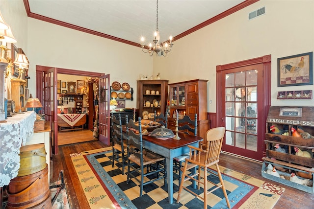 dining room with hardwood / wood-style flooring, visible vents, a notable chandelier, and ornamental molding