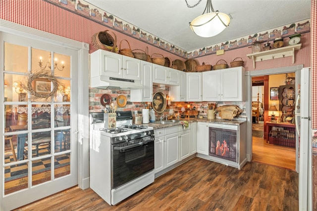 kitchen featuring under cabinet range hood, white range with gas stovetop, white cabinetry, and dark wood-style flooring