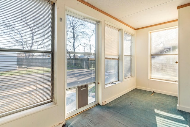 unfurnished sunroom with baseboards, ornamental molding, and carpet