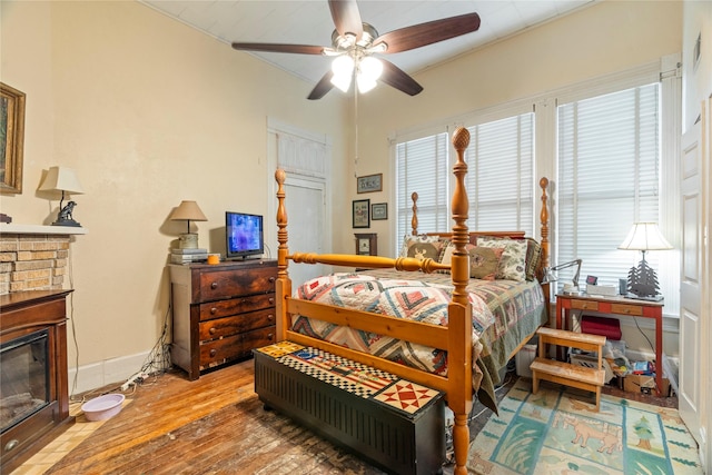 bedroom with hardwood / wood-style flooring, baseboards, a fireplace, and ceiling fan