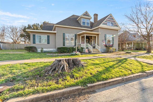 view of front of home with roof with shingles, a chimney, a front yard, and fence