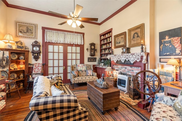 living room with heating unit, wood finished floors, ceiling fan, crown molding, and a fireplace