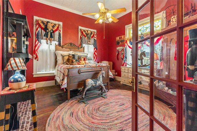 bedroom featuring baseboards, ornamental molding, wood finished floors, and multiple windows