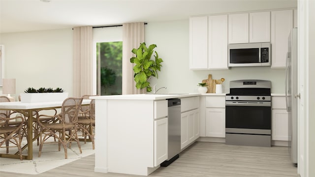 kitchen with light wood-type flooring, light countertops, appliances with stainless steel finishes, a peninsula, and white cabinets