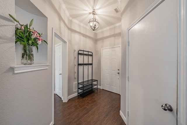 hallway with visible vents, baseboards, dark wood finished floors, ornamental molding, and a notable chandelier