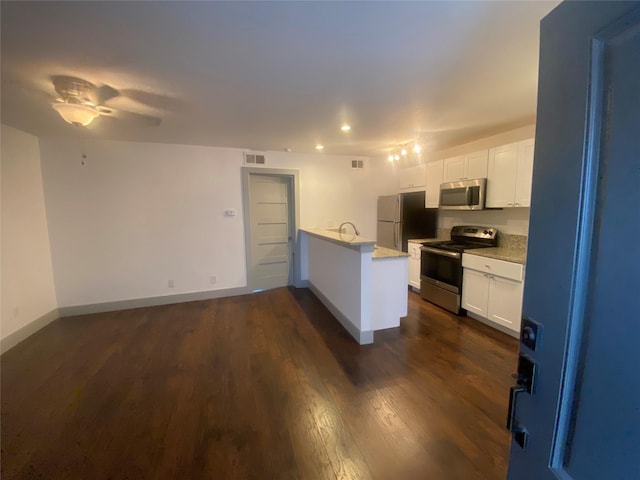 kitchen featuring visible vents, dark wood-style flooring, appliances with stainless steel finishes, a peninsula, and a sink