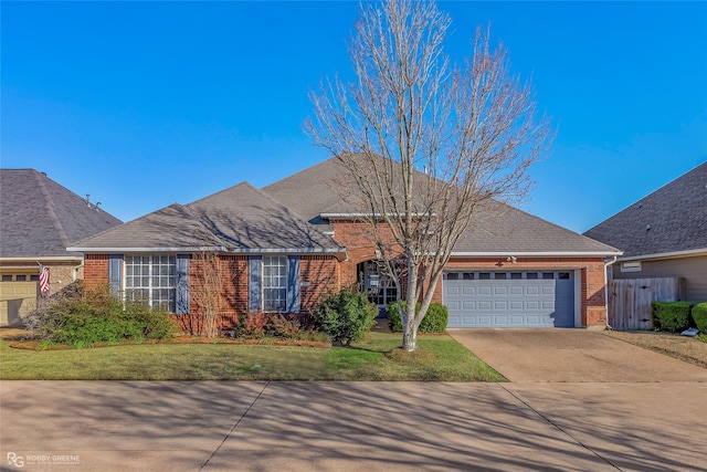 view of front of home featuring a front yard, fence, an attached garage, concrete driveway, and brick siding